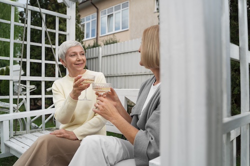 Senior souriante partageant un moment de convivialité avec son auxiliaire de vie sur une terrasse — aide à domicile à Rueil-Malmaison, AGMAD 92
